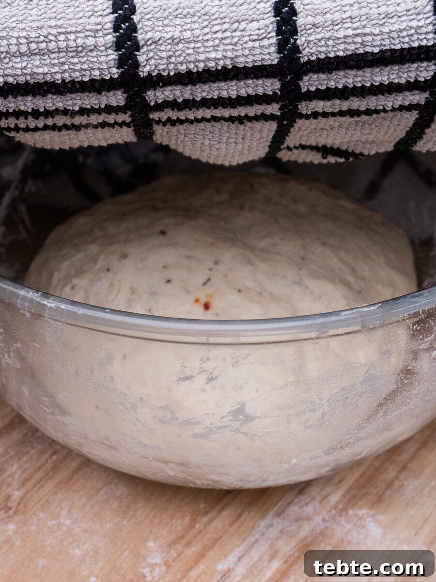 Crispy Garlic Pizza Bread Recipe — Cheesy Garlic Pull-Apart Loaf 26 Pizza Bread dough in a mixing bowl being covered over with a damp towel