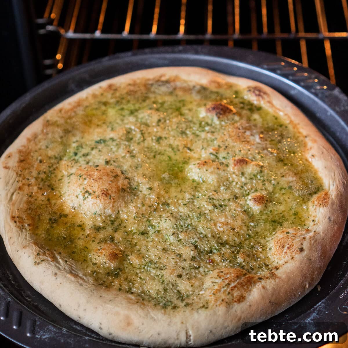 Crispy Garlic Pizza Bread Recipe — Cheesy Garlic Pull-Apart Loaf 32 Taking out a cooked Garlic Pizza Bread out of the oven using an orange oven glove