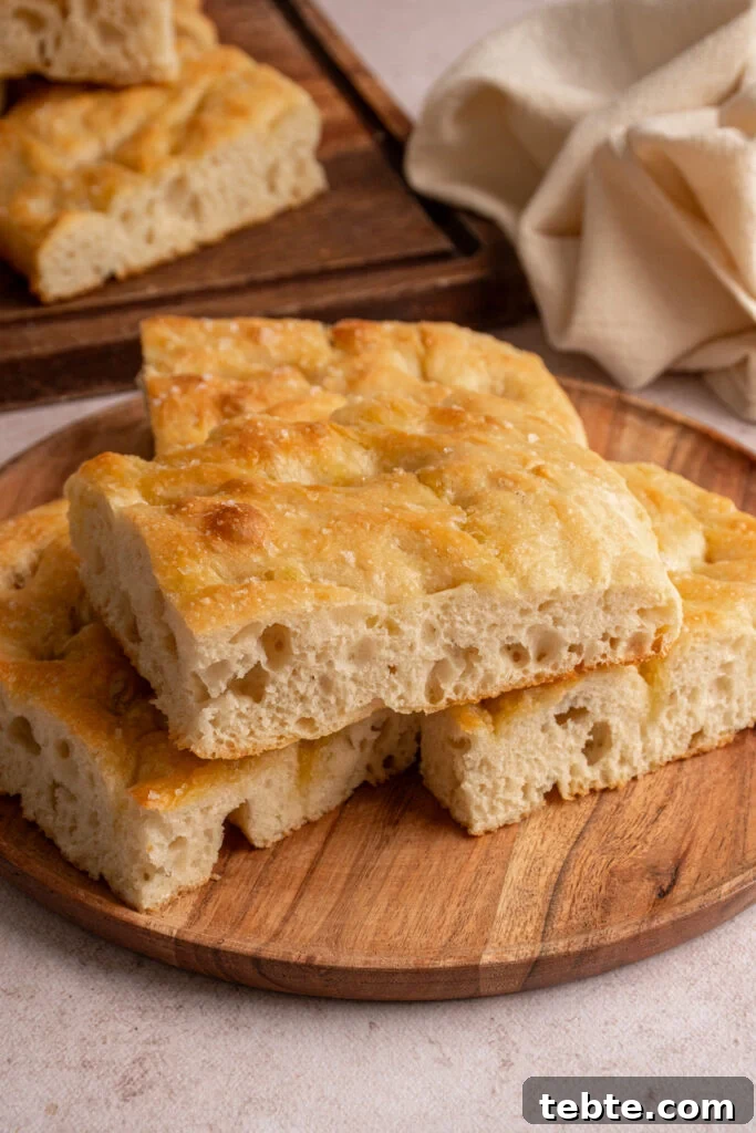 Authentic Italian Focaccia Bread Recipe 2 Pieces of focaccia bread on a wooden plate.
