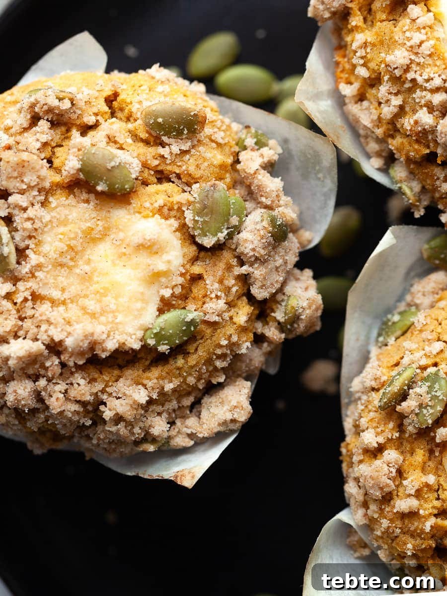 Close up of agluten free pumpkin cream cheese muffin on a plate topped with pumpkin seed streusel