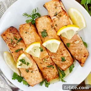 ninja foodie grill salmon on a plate with lemon garlic butter sauce and parsley