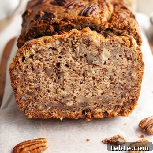 A close up of a slice of pecan banana bread on parchment paper.