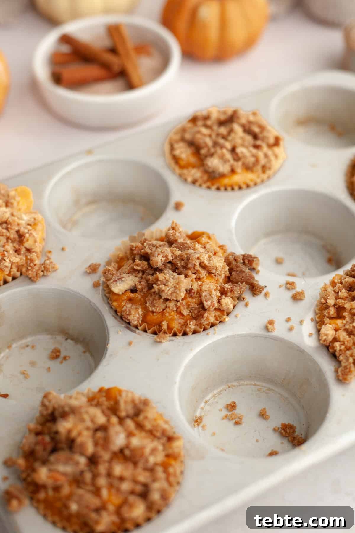 Pumpkin Pecan Muffins with Crunchy Pecan Streusel 7 Unbaked pumpkin muffins with streusel in a muffin pan.