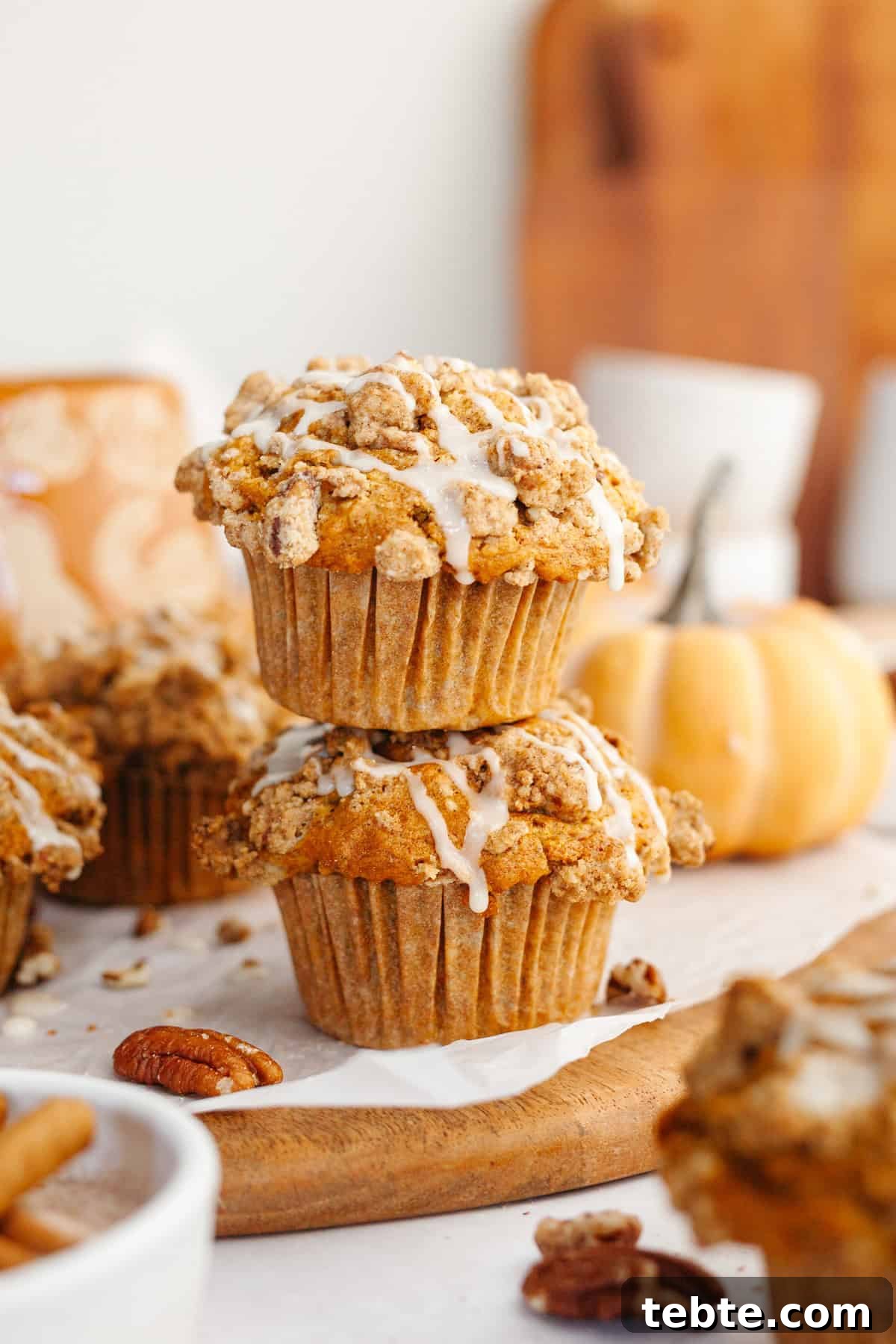 Pumpkin Pecan Muffins with Crunchy Pecan Streusel 9 A stack of two pecan pumpkin muffins on a wooden board.