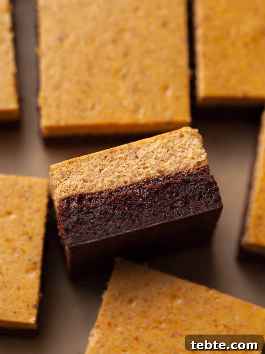 Gluten-Free Pumpkin Cheesecake Brownies Recipe for Fall Baking 2 a slice of gluten free pumpkin cheesecake brownies laying on parchment paper.