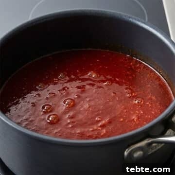 Chinese sweet and sour sauce simmering in nonstick saucepan. 