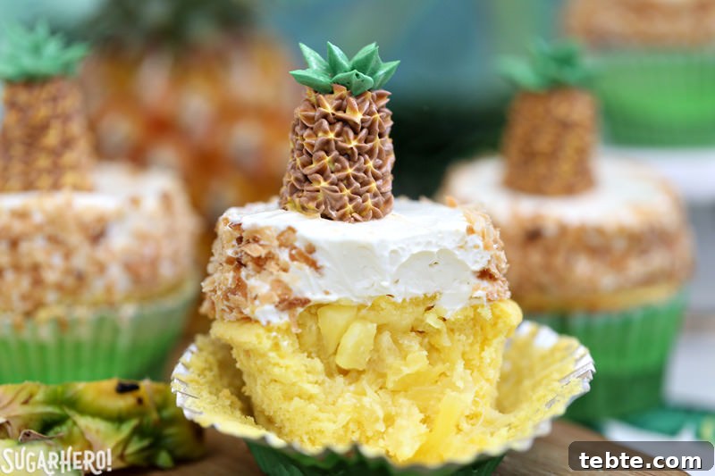 Pineapple Cupcake with coconut buttercream and fresh pineapple spilling out of the center | From SugarHero.com