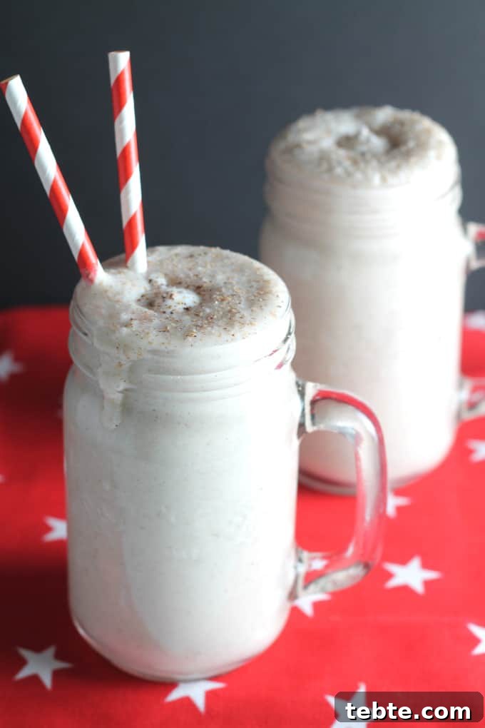 Gingerbread Smoothie Recipe: Spiced Holiday Breakfast Drink 2 Two Gingerbread Smoothie christmas drinks served in glass mugs with red and white straws in one of the mugs.