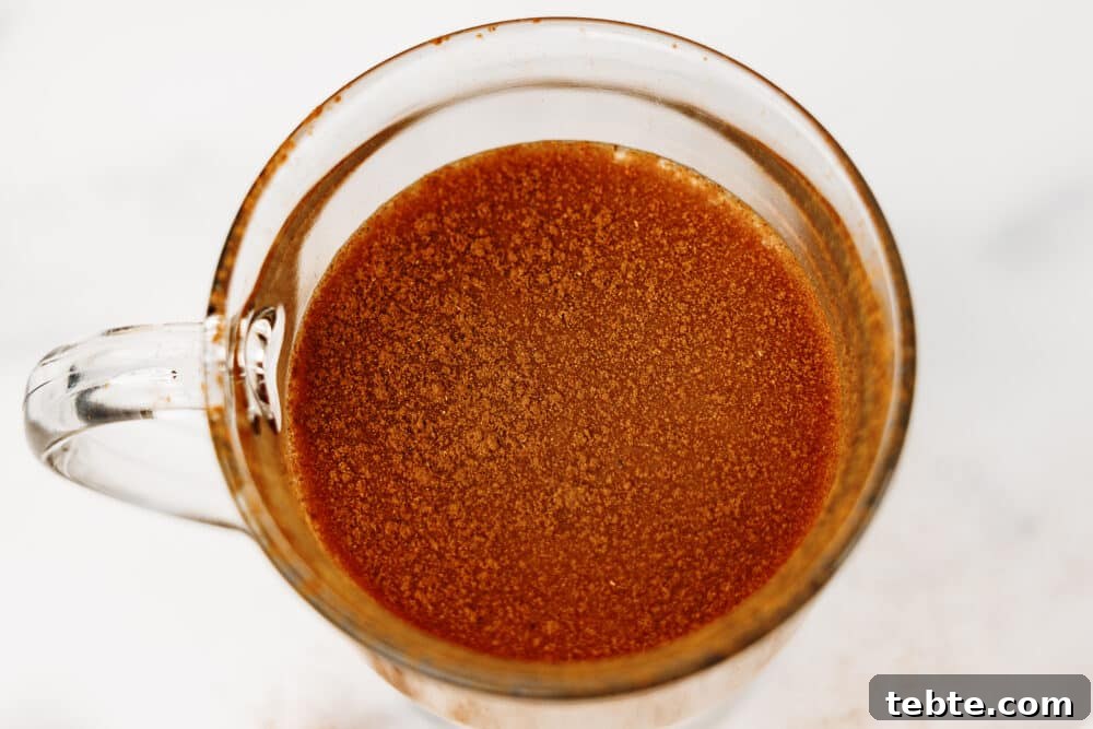 Overhead close-up of protein chai latte in a clear mug topped with cinnamon.