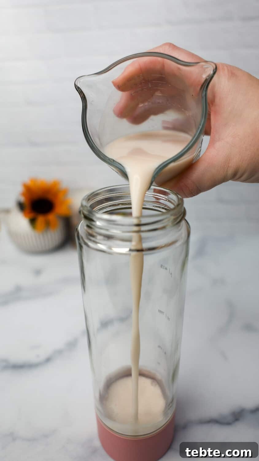 Almond milk being poured into a blender bottle.