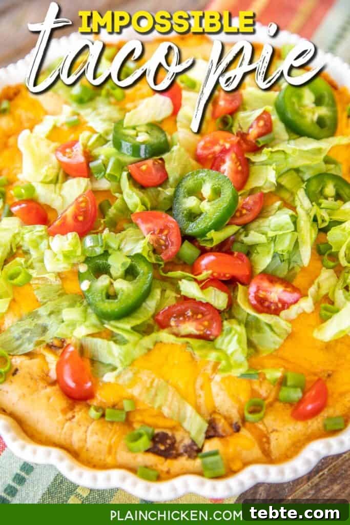 taco pie topped with lettuce and tomato in a pie plate