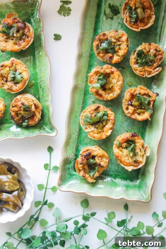 Jalapeño Popper Bread with Creamy Dipping Oil Recipe 10 Jalapeno popper taco cups on a green rectangular plate, with a bowl of jalapenos on the side.