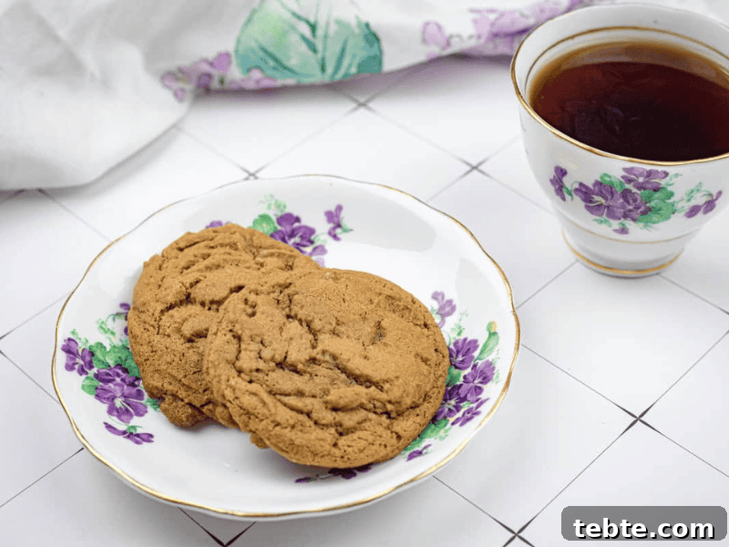 13 Christmas Cookies That Win Every Office Cookie Exchange 4 Two cookies on a floral plate next to a cup of black coffee, with a white and purple cloth in the background on a tiled surface.