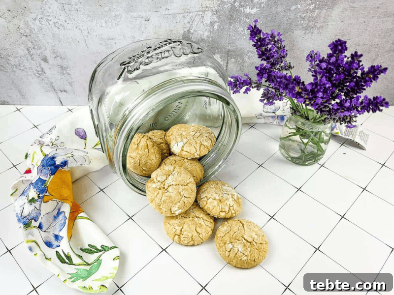 13 Christmas Cookies That Win Every Office Cookie Exchange 10 A jar of White Chocolate Crinkle Cookies next to lavender flowers.