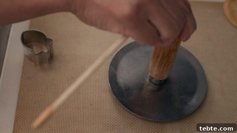 5-Minute Dalgona Candy Recipe: Crispy Korean Sugar Treat 13 A flat metal round disk with a wooden handle is pressing down the dalgona candy.