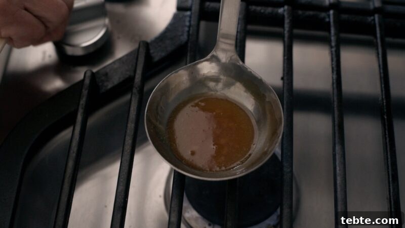 5-Minute Dalgona Candy Recipe: Crispy Korean Sugar Treat 9 Sugar has caramelized to amber color in a ladle over stove.