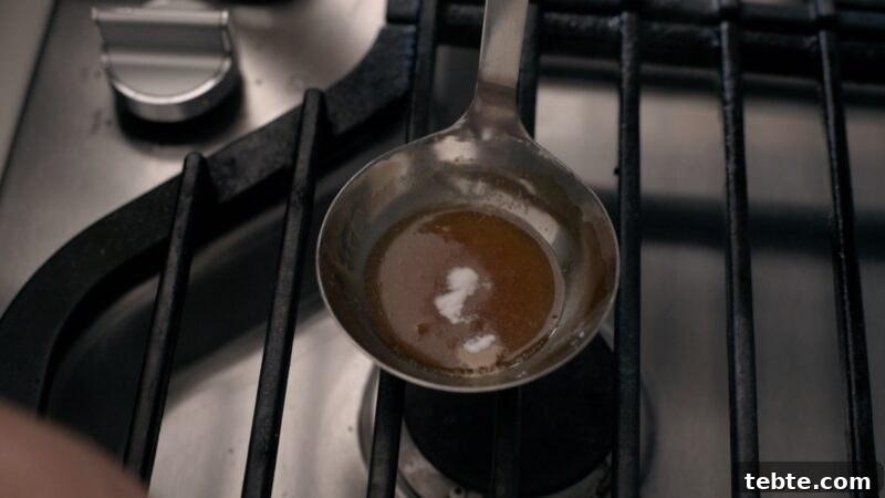 5-Minute Dalgona Candy Recipe: Crispy Korean Sugar Treat 10 A small amount of baking soda is added to the caramelized sugar in a ladle.