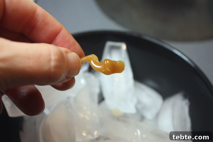 Classic English Toffee Recipe: Crispy, Buttery Homemade Treat 5 Piece of dripped hard candy being held over the ice.