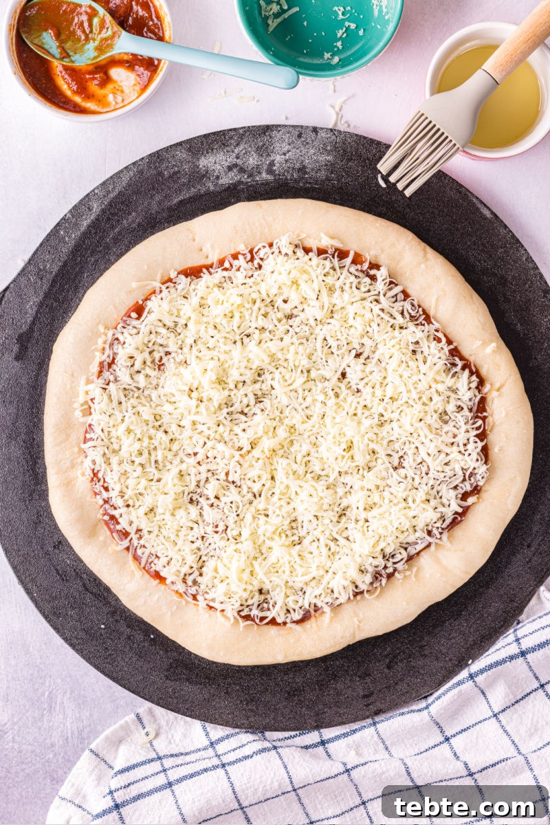 par baked pizza crust topped with pizza sauce and shredded mozzarella cheese