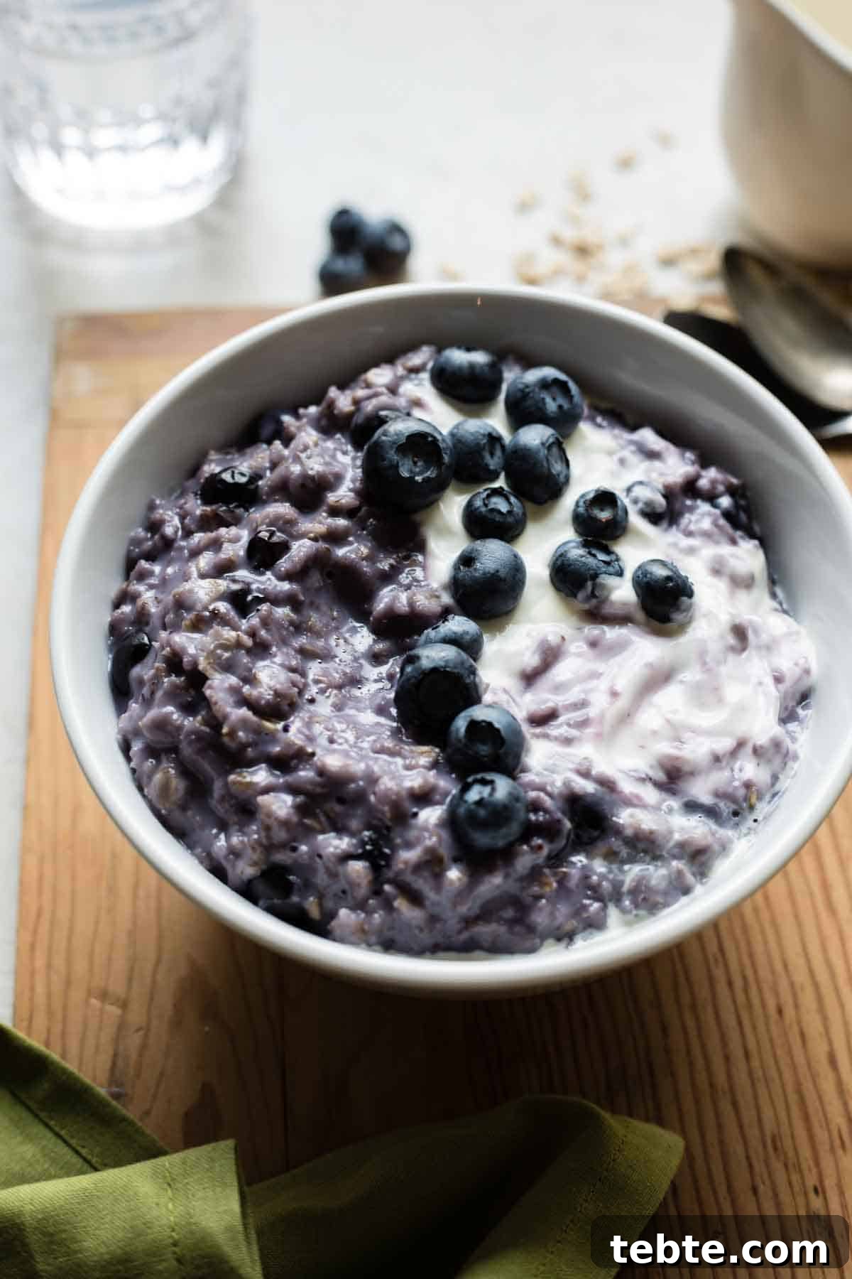 Bowl of blueberry oatmeal topped with creamy vanilla yogurt.
