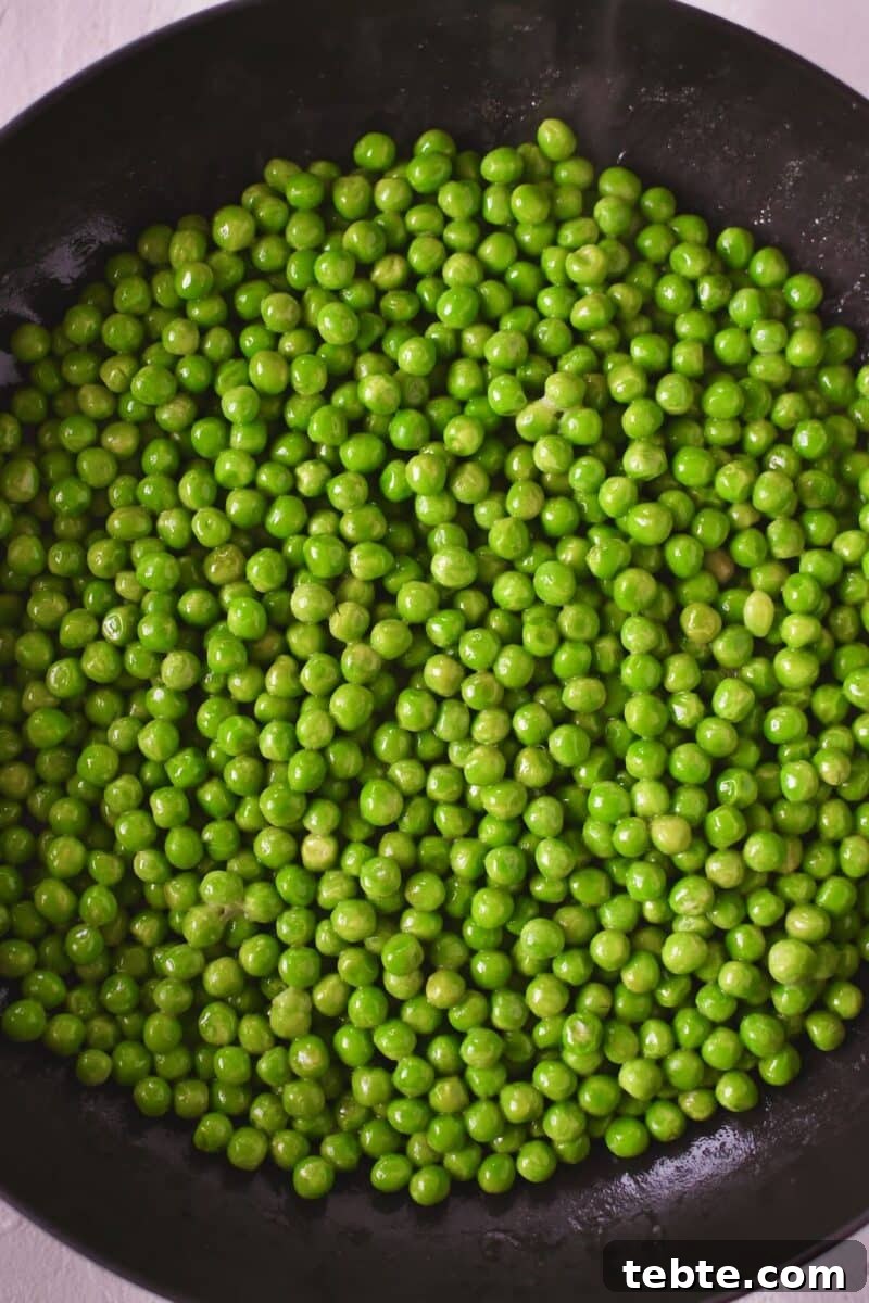Creamy Pea Salad with Bacon and Red Onion 4 Peas warming in a pan with some butter on the stove.
