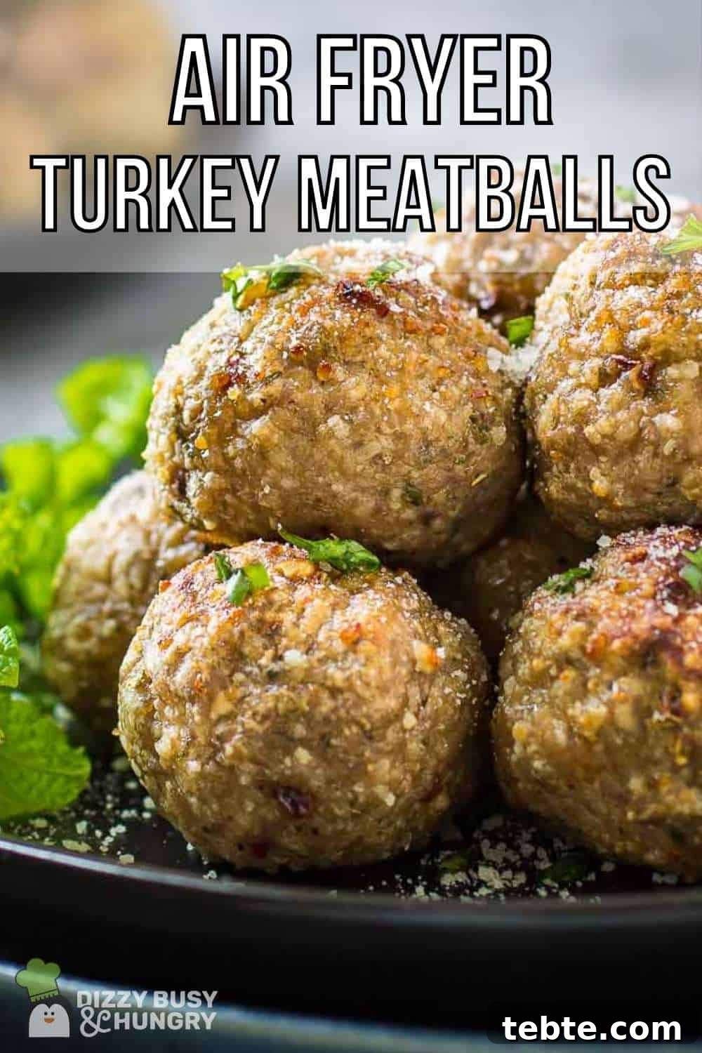Crispy Air Fryer Turkey Meatballs with Garlic and Herbs 2 Side close up shot of multiple meatballs stacked on a black plate garnished with herbs and parmesan cheese.