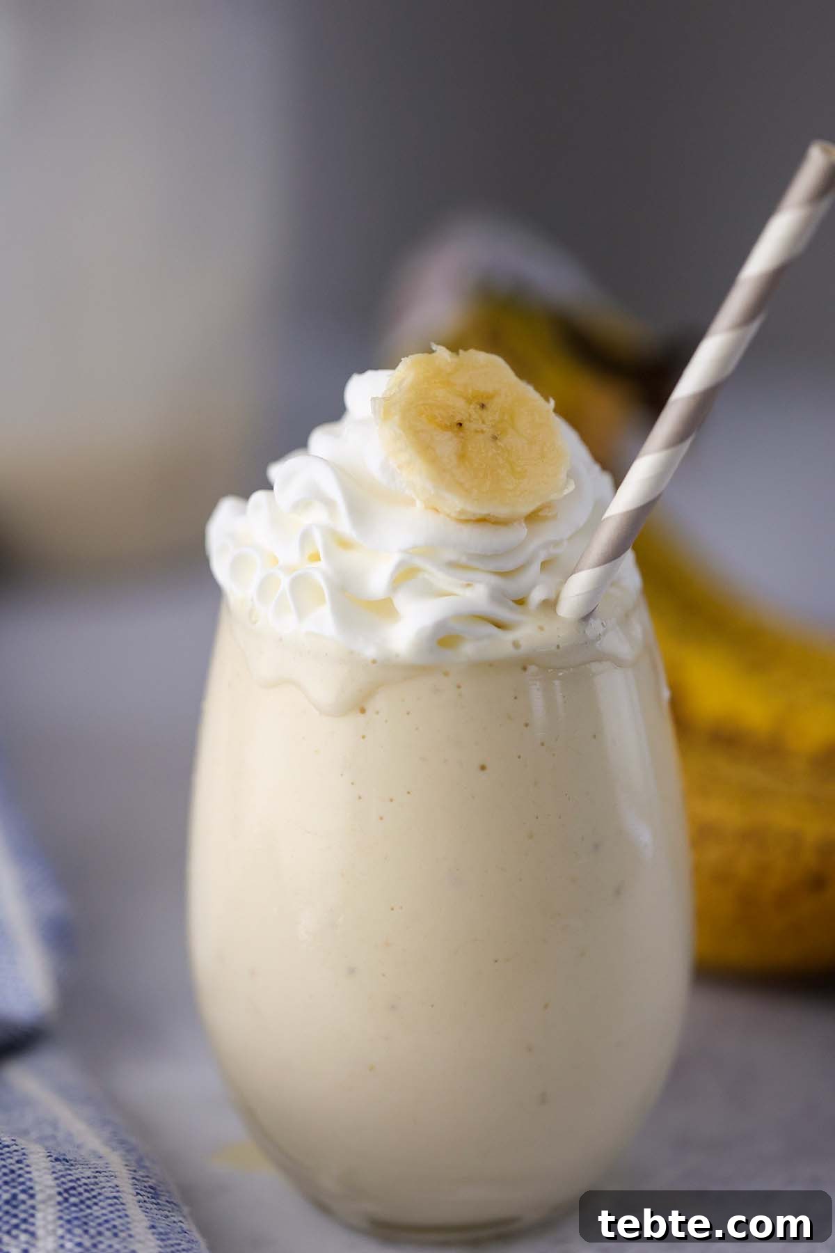 Creamy Banana Milkshake Recipe for Thick, Frosty Results 5 banana milkshake in a glass with whipped cream on top.