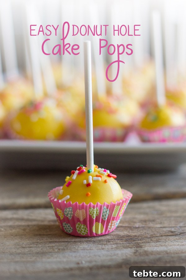 Easy Donut Hole Cake Pop in a mini muffin liner, with a platter of more cake pops in the background.