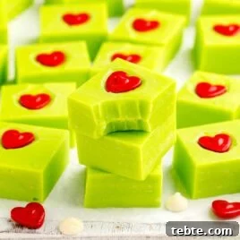 Green Grinch Fudge Recipe: Festive Candy for Holiday Gifting 9 a close up shot of pieces of Grinch Fudge stacked on top of each other with one having a bite taken out of it