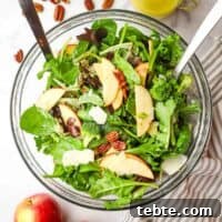 Crisp Apple and Pecan Salad with Maple Vinaigrette 12 Overhead view of a bowl of mixed apple pecan salad with serving utensils in it.