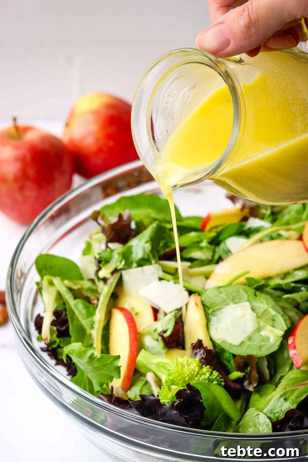 Crisp Apple and Pecan Salad with Maple Vinaigrette 4 adding maple dressing to a bowl of apple pecan salad