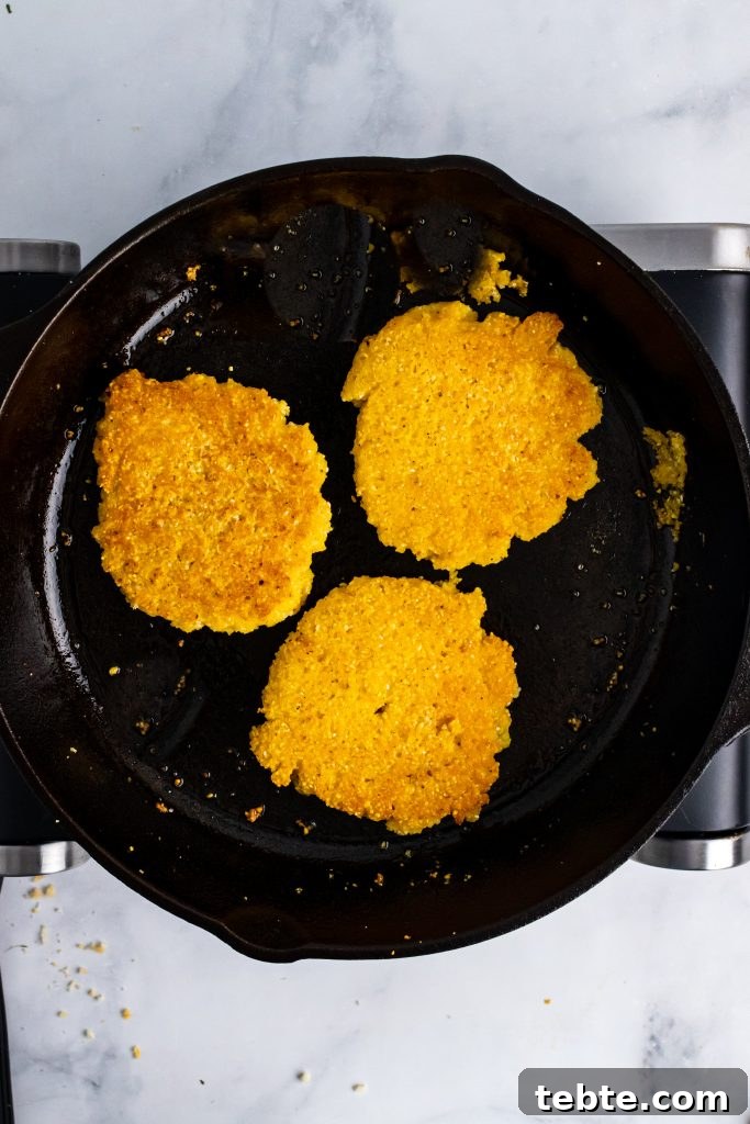 three fried hot water cornbread cakes in a cast iron skillet