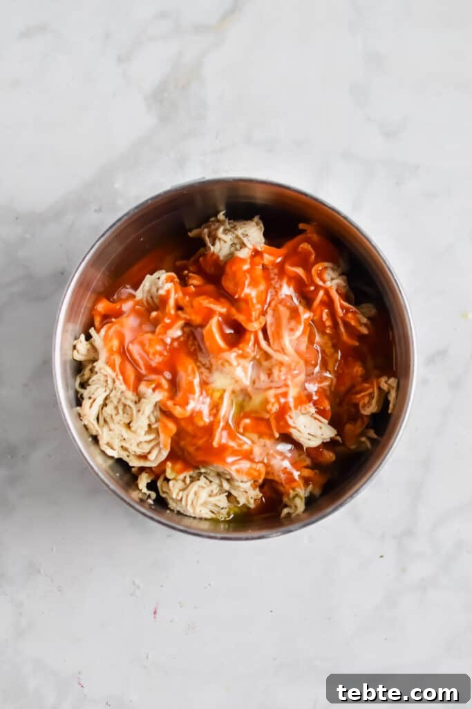 The chicken, butter, and hot sauce are mixed in a bowl.