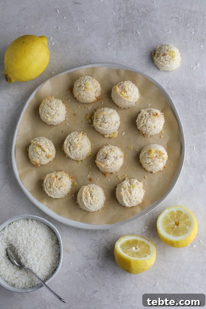 Lemon Almond Macaroons Recipe: Zesty Gluten-Free Cookies 2 Lemon Almond Flour Macaroons on parchment lined plate with lemons and shredded coconut on the side