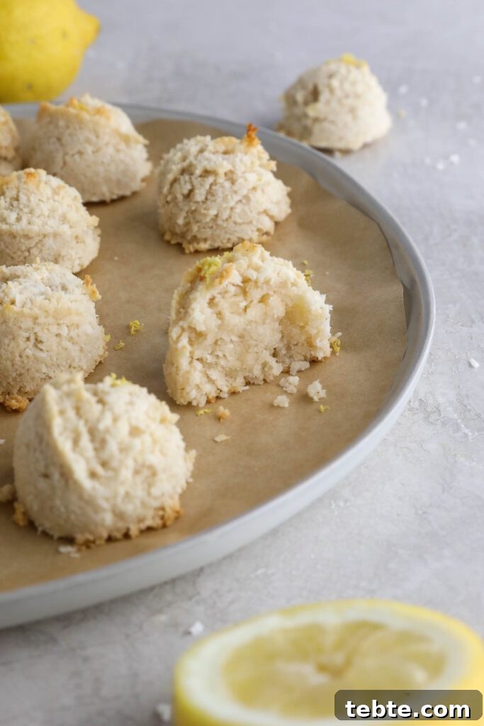 Lemon Almond Macaroons Recipe: Zesty Gluten-Free Cookies 9 Lemon Almond Flour Macaroons on parchment lined plate with lemons and shredded coconut on the side