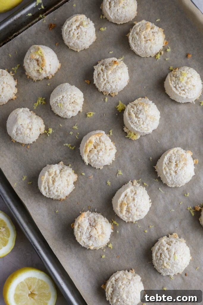Lemon Almond Macaroons Recipe: Zesty Gluten-Free Cookies 5 Lemon Almond Flour Macaroons on parchment lined baking sheet with lemons on the side topped with lemon zest