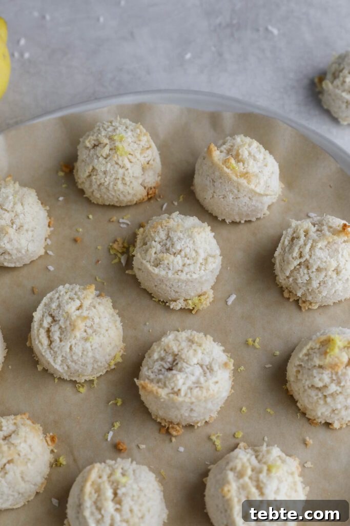 Lemon Almond Macaroons Recipe: Zesty Gluten-Free Cookies 8 Lemon Almond Flour Macaroons on parchment lined plate with lemons and shredded coconut on the side