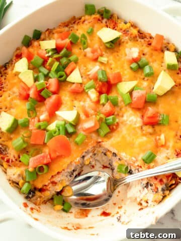 Spoon taking out a piece of Mexican casserole.