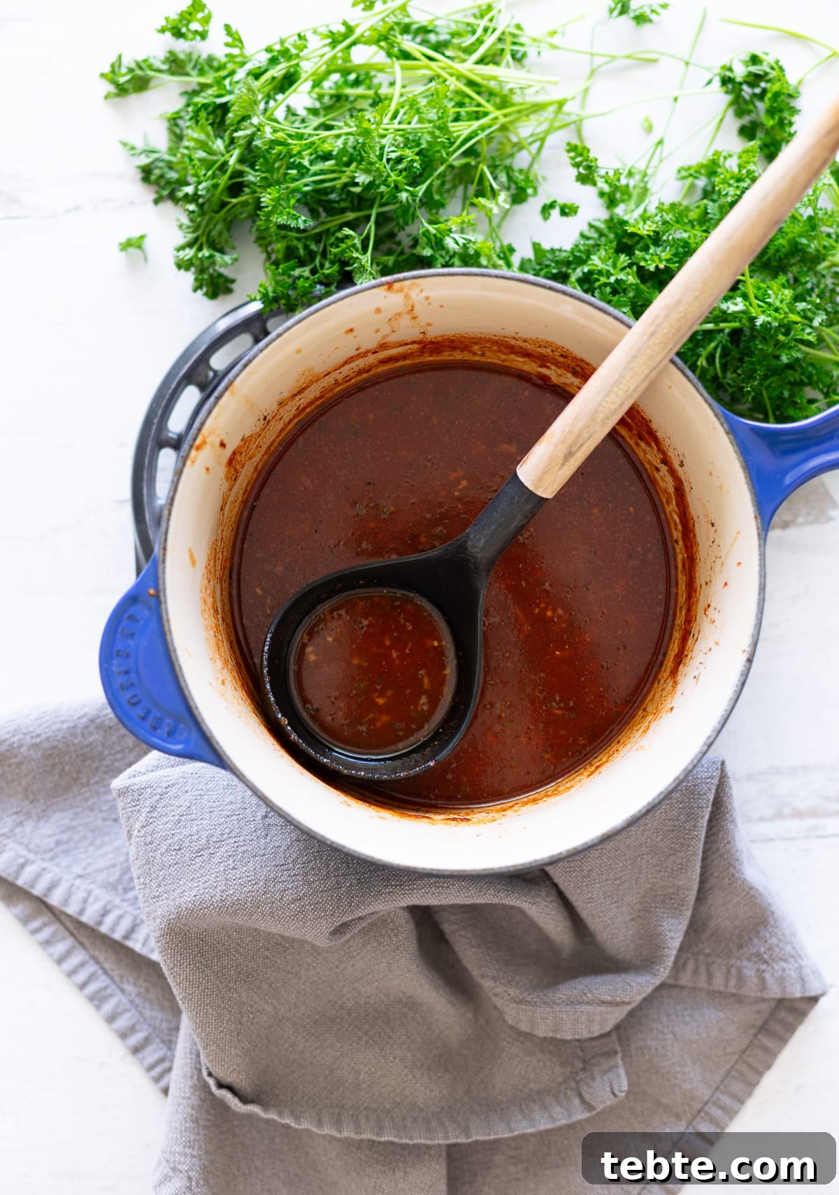 Homemade Red Enchilada Sauce Recipe for Authentic Flavor 3 Person using a ladle to serve homemade enchilada sauce.
