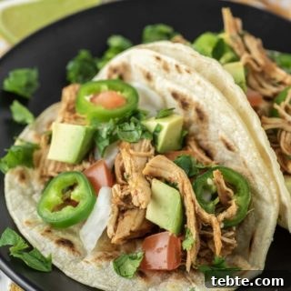 two Instant pot chicken tacos on black plate