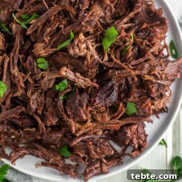 Shredded beef made with Instant Pot on white plate.