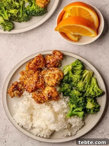 A plate of breaded orange chicken with white rice and steamed broccoli.