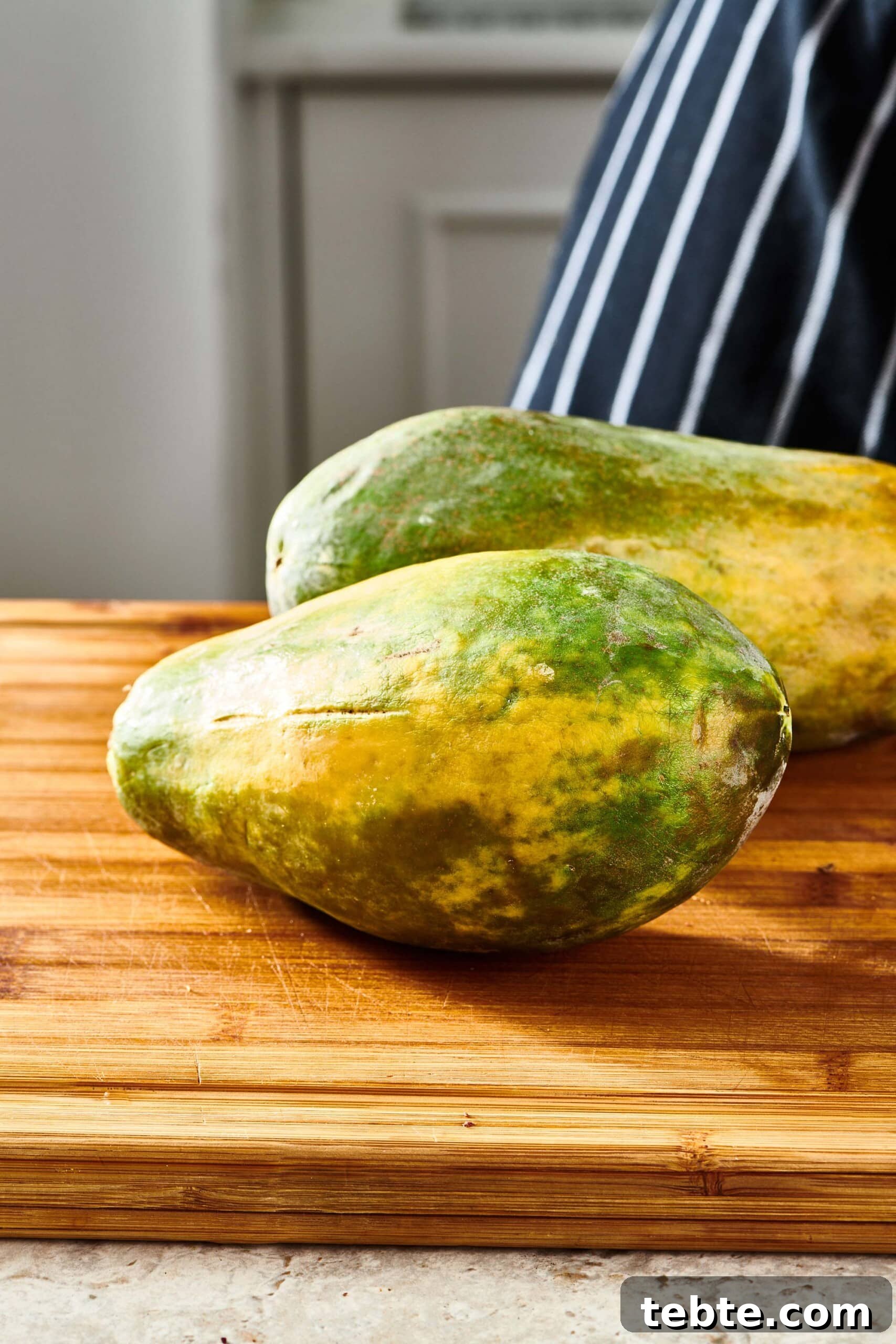 How to Slice and Prepare a Papaya Quickly 2 Two Papayas on a wooden cutting board.