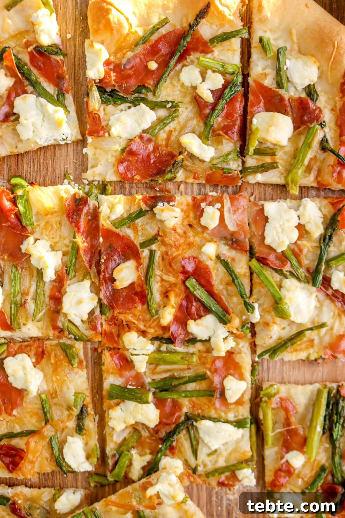 Asparagus, Caramelized Onion & Prosciutto Flatbread with Goat Cheese 3 close up of sliced asparagus and prosciutto flatbread on wood board.