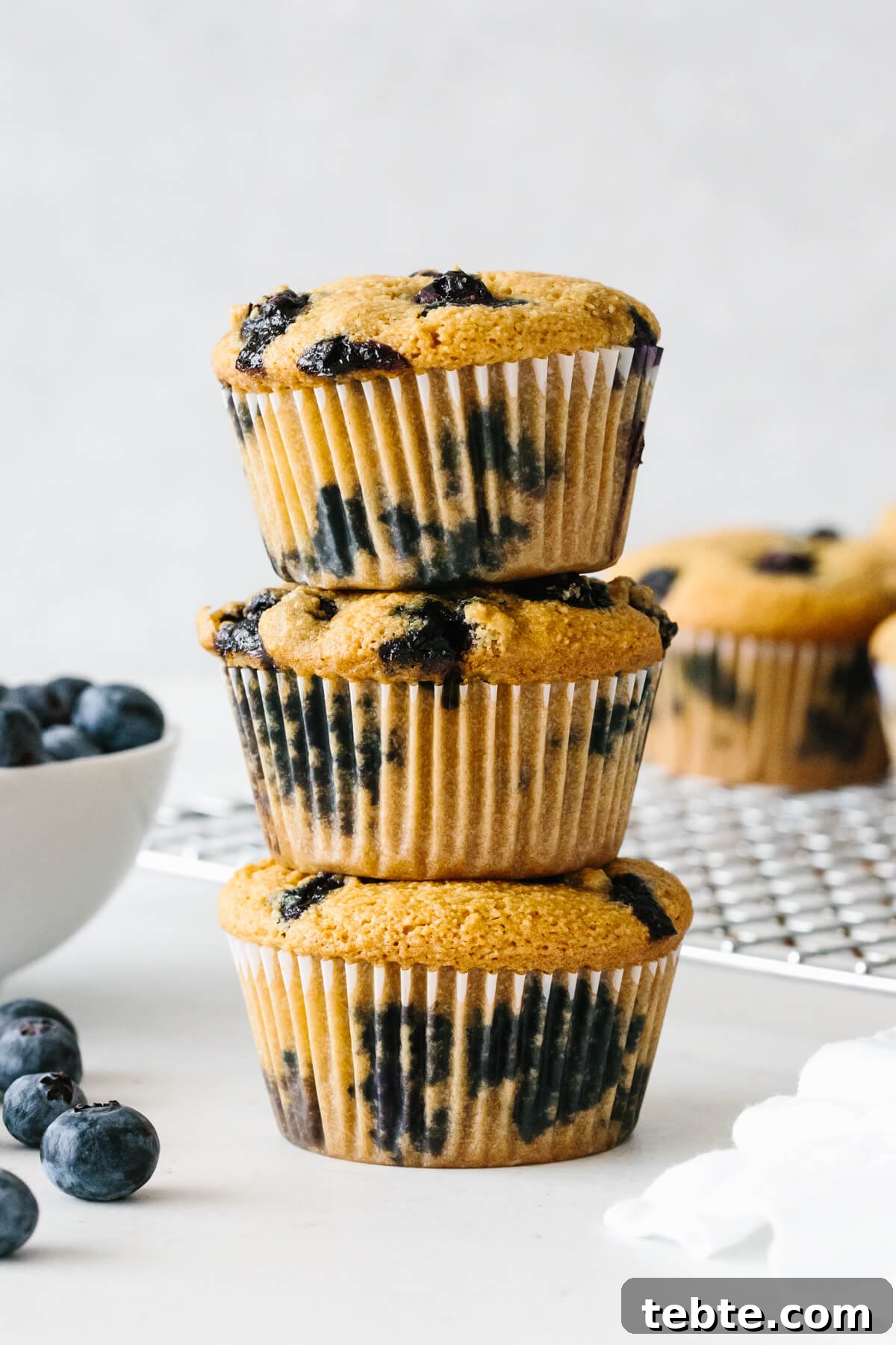 Three paleo blueberry muffins stacked on top of each other.