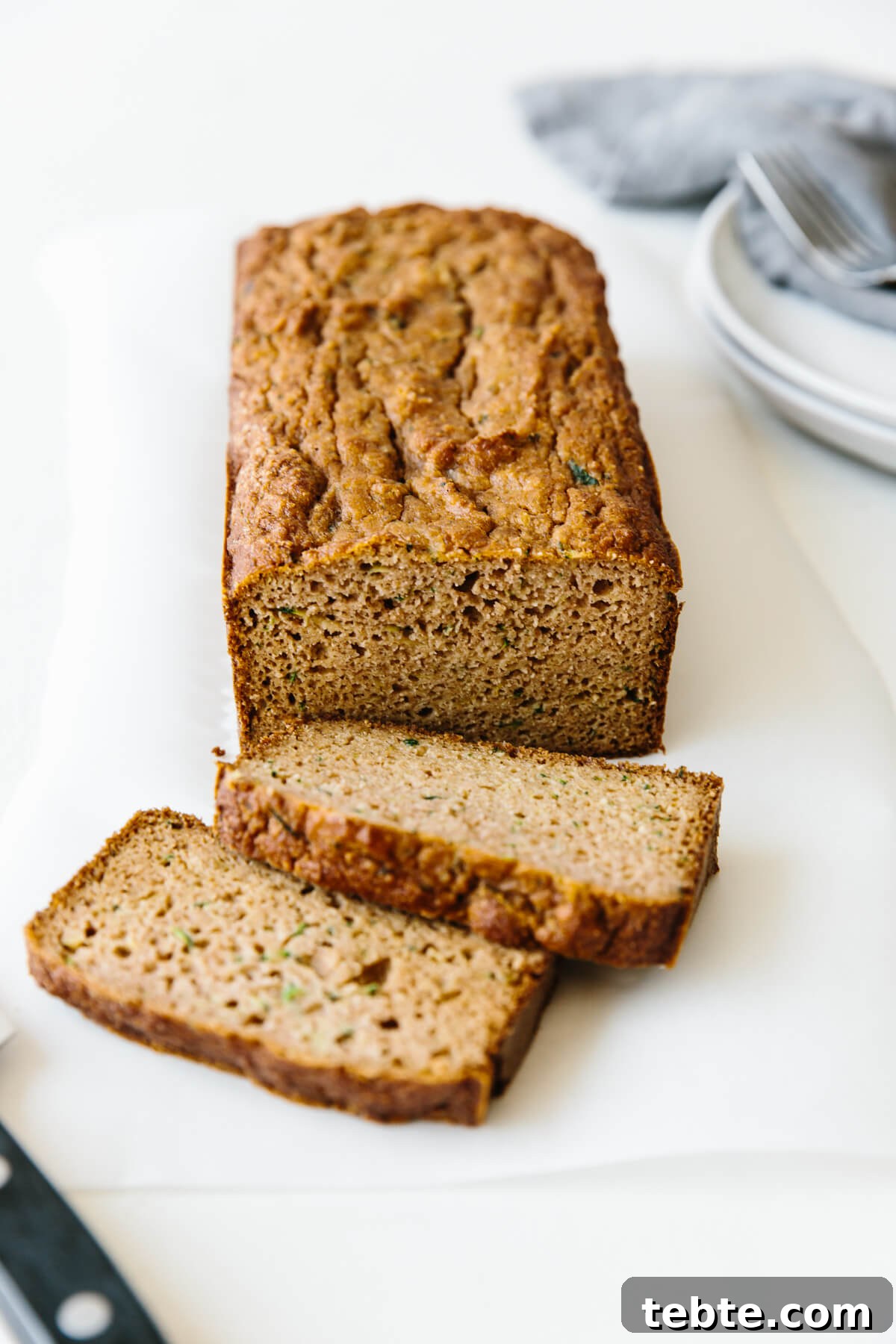 Paleo zucchini bread on a table with two slices from the loaf.