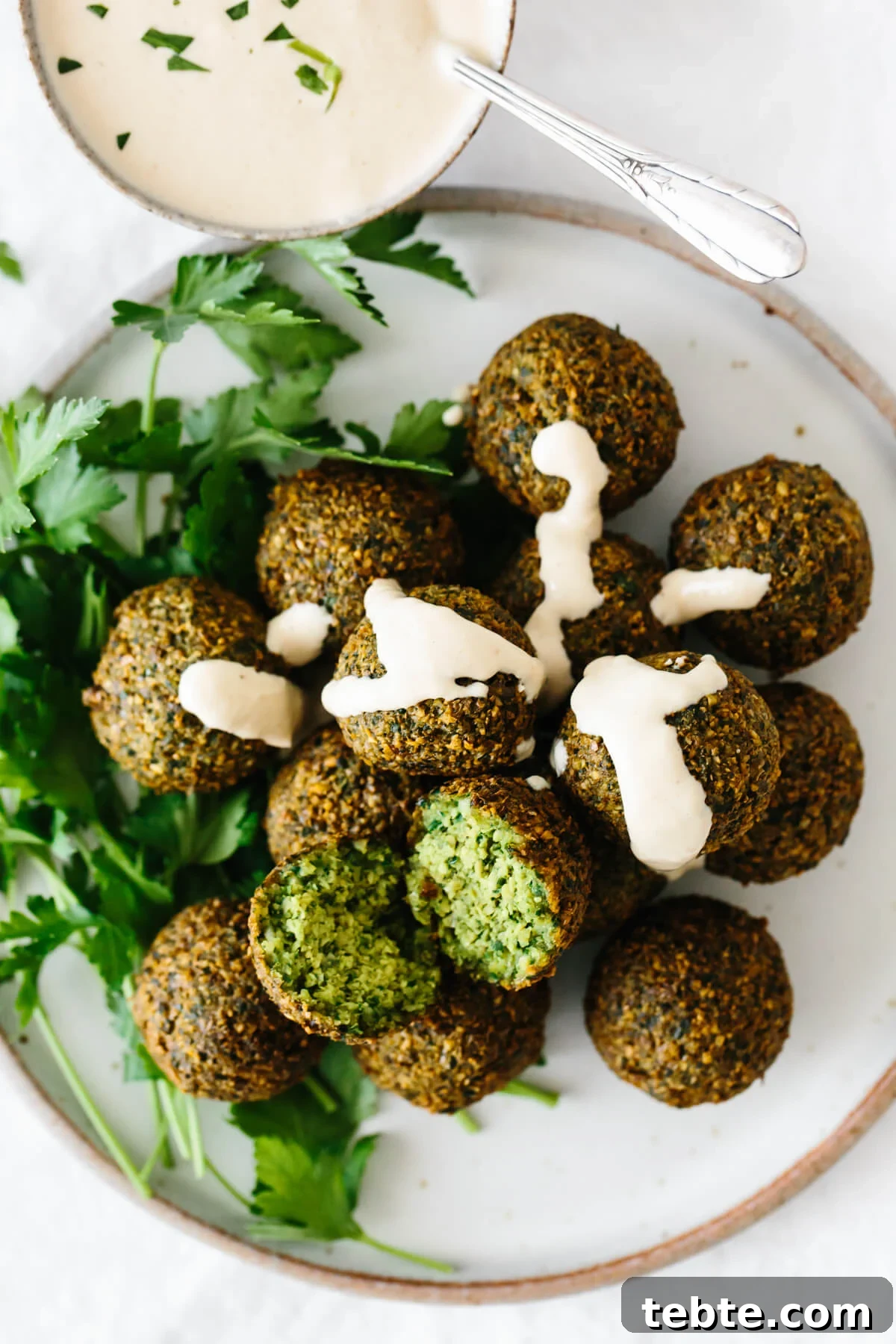 A plate of falafel drizzled with tahini sauce.