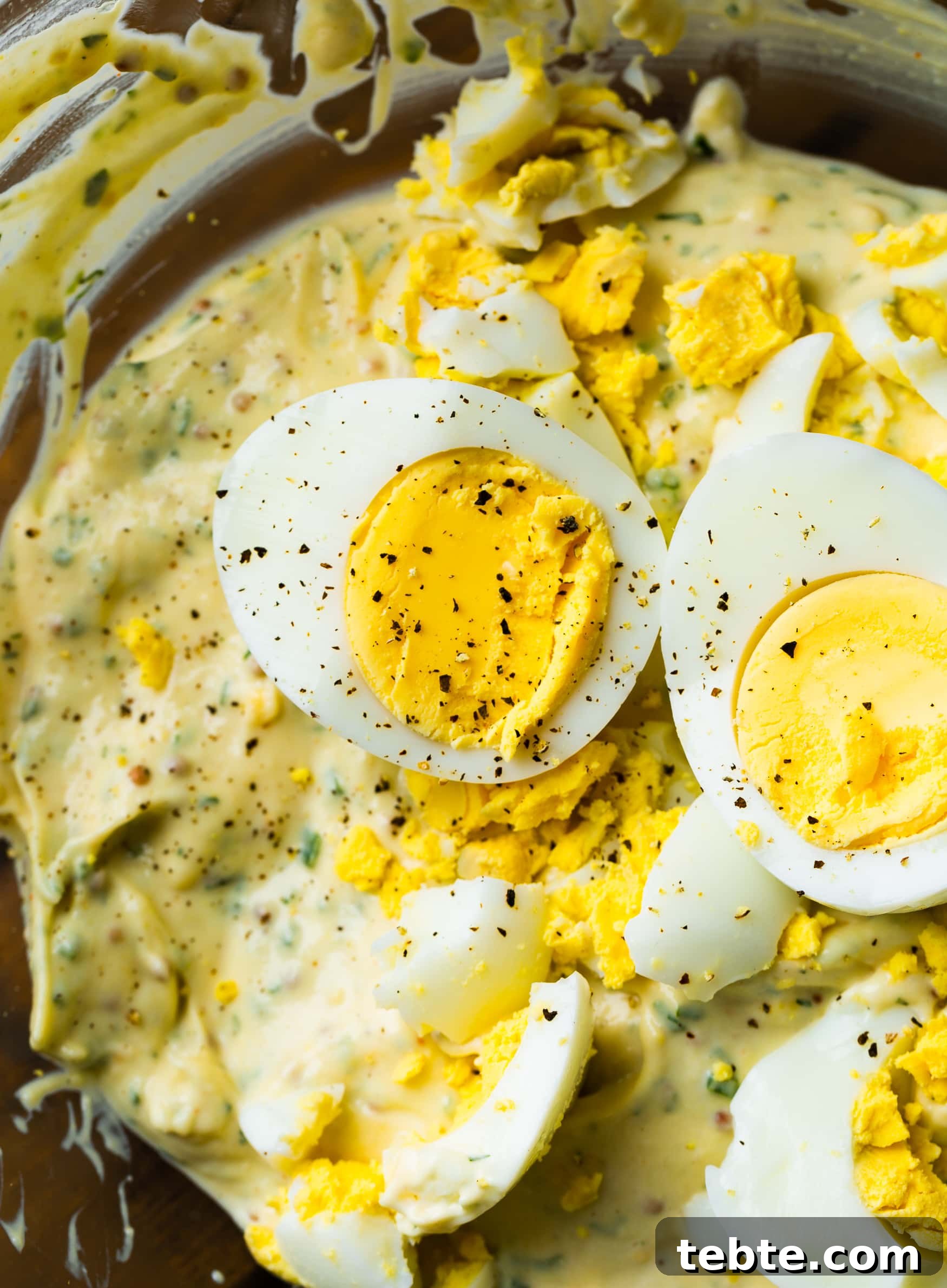 The BEST Egg Salad Sandwich Recipe a photo of hard boiled eggs that have been halved with the yolks showing that have been topped with pepper.