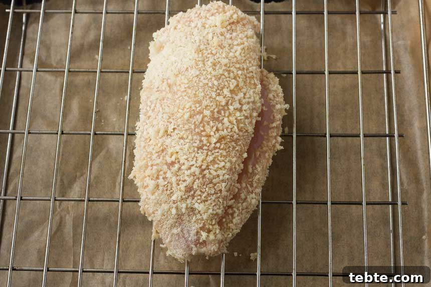 Crispy Baked Chicken Stuffed with Ham and Melted Cheese 4 Crispy baked ham and cheese stuffed chicken on a grill from above before cooking.