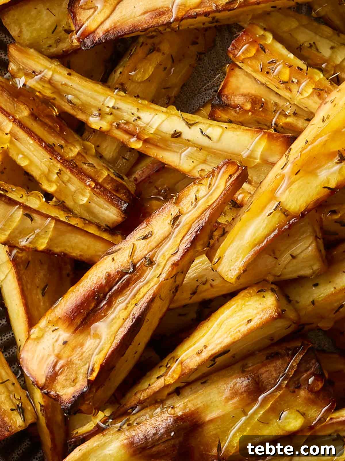 Crispy Roasted Parsnips with Honey and Rosemary 3 A close up of parsnips that have been roasted, drizzled with honey, oil and thyme.
